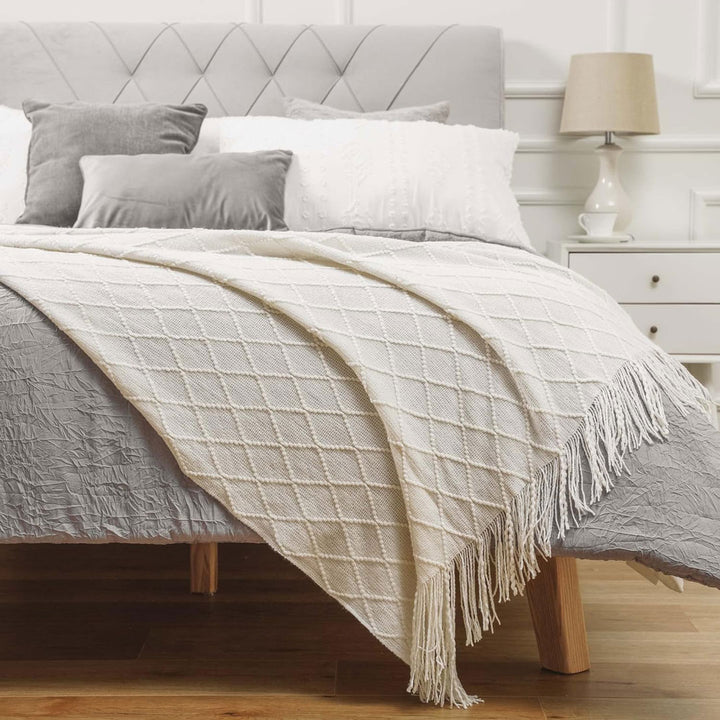 Knit Throw Blanket with Tassels in Cream Color on Bed. Size 130-150 cm