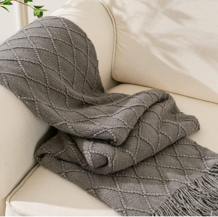 Knit Throw Blanket with Tassels in Grey Color. On sofa. Size 130-150 cm