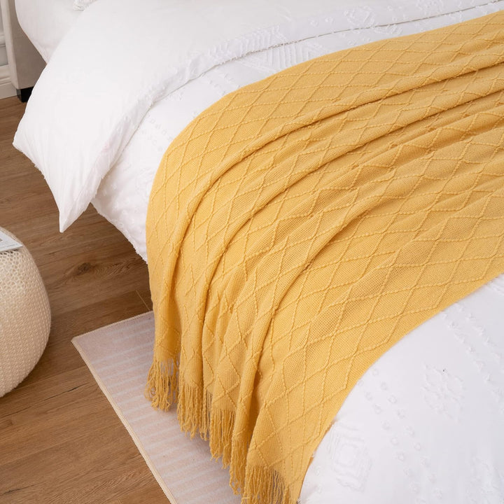 Knit Throw Blanket with Tassels in Mustard Color. On bed. Size 130-150 cm