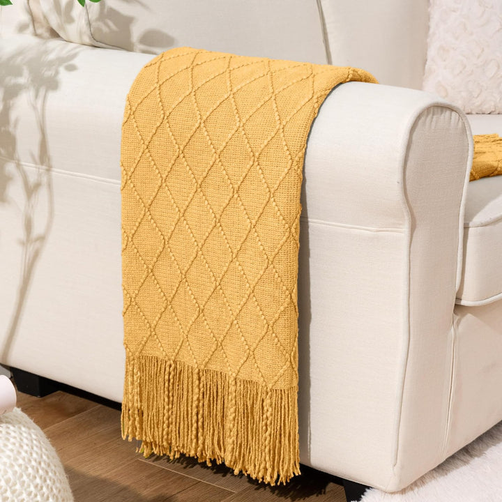 Knit Throw Blanket with Tassels in Mustard Color. On sofa. Size 130-150 cm